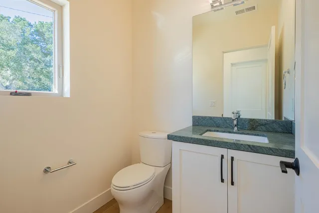 a bathroom with a granite countertop sink a toilet and a mirror