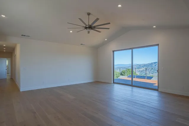 an empty room with wooden floor fan and windows