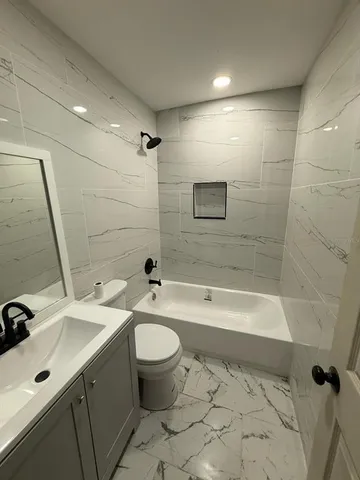 a bathroom with a sink toilet a mirror a bath tub and shower