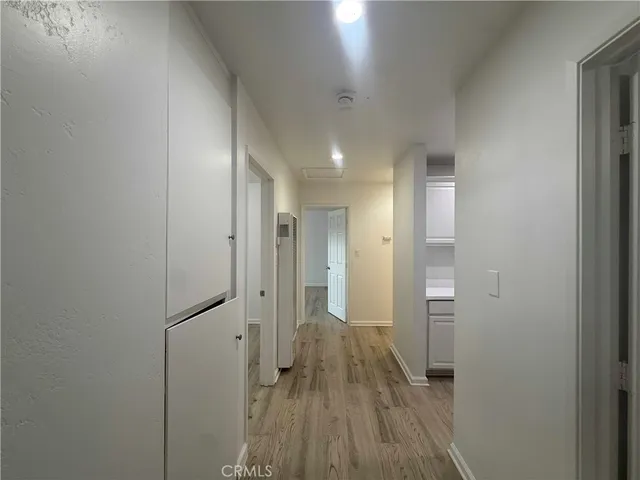 a view of a hallway to an empty room and wooden floor