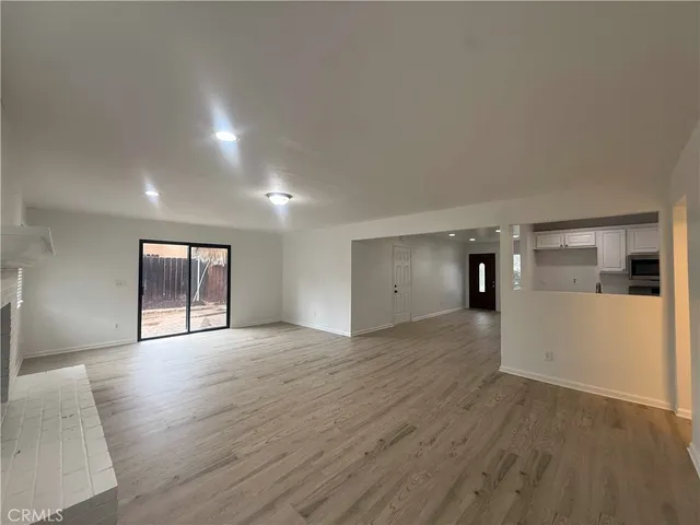 a view of empty room with wooden floor and window