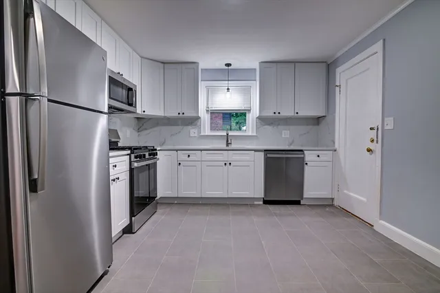 a kitchen with white cabinets stainless steel appliances and a refrigerator