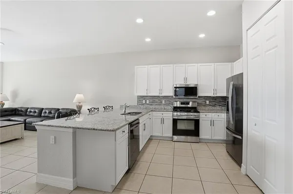 a kitchen with stainless steel appliances granite countertop a stove top oven a sink dishwasher and a refrigerator with wooden cabinets