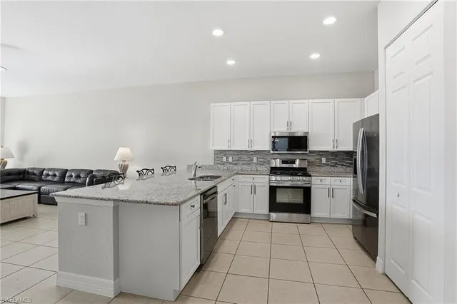 a kitchen with stainless steel appliances granite countertop a stove top oven a sink dishwasher and a refrigerator with wooden cabinets