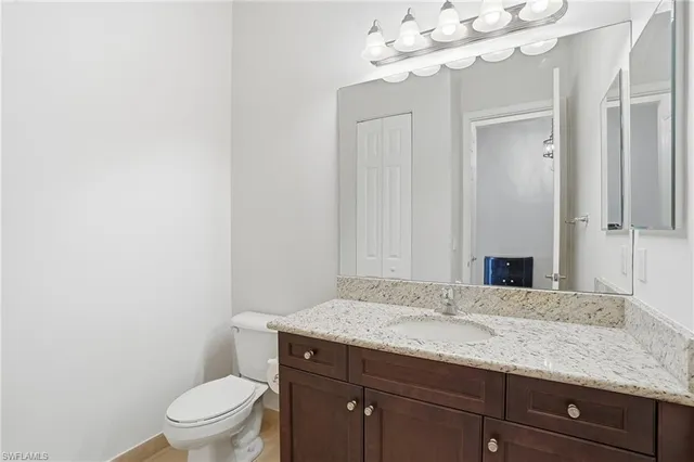 a bathroom with a granite countertop sink a toilet and mirror