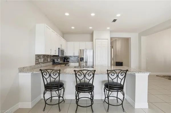 a kitchen with stainless steel appliances a white table chairs and a refrigerator