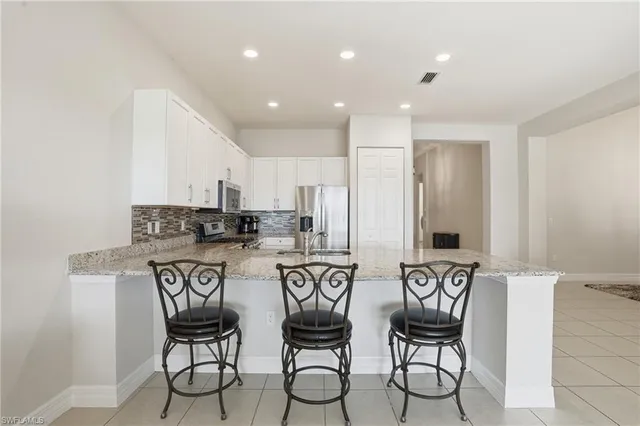a kitchen with stainless steel appliances a white table chairs and a refrigerator