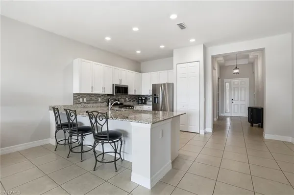 a kitchen with stainless steel appliances kitchen island granite countertop a refrigerator and a stove top oven