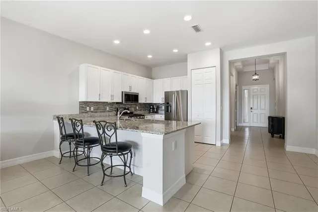 a kitchen with stainless steel appliances kitchen island granite countertop a refrigerator and a stove top oven