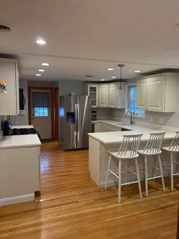 a kitchen with stainless steel appliances kitchen island granite countertop a table chairs sink and cabinets