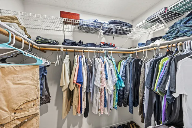 a view of walk in closet with clothes and shoes