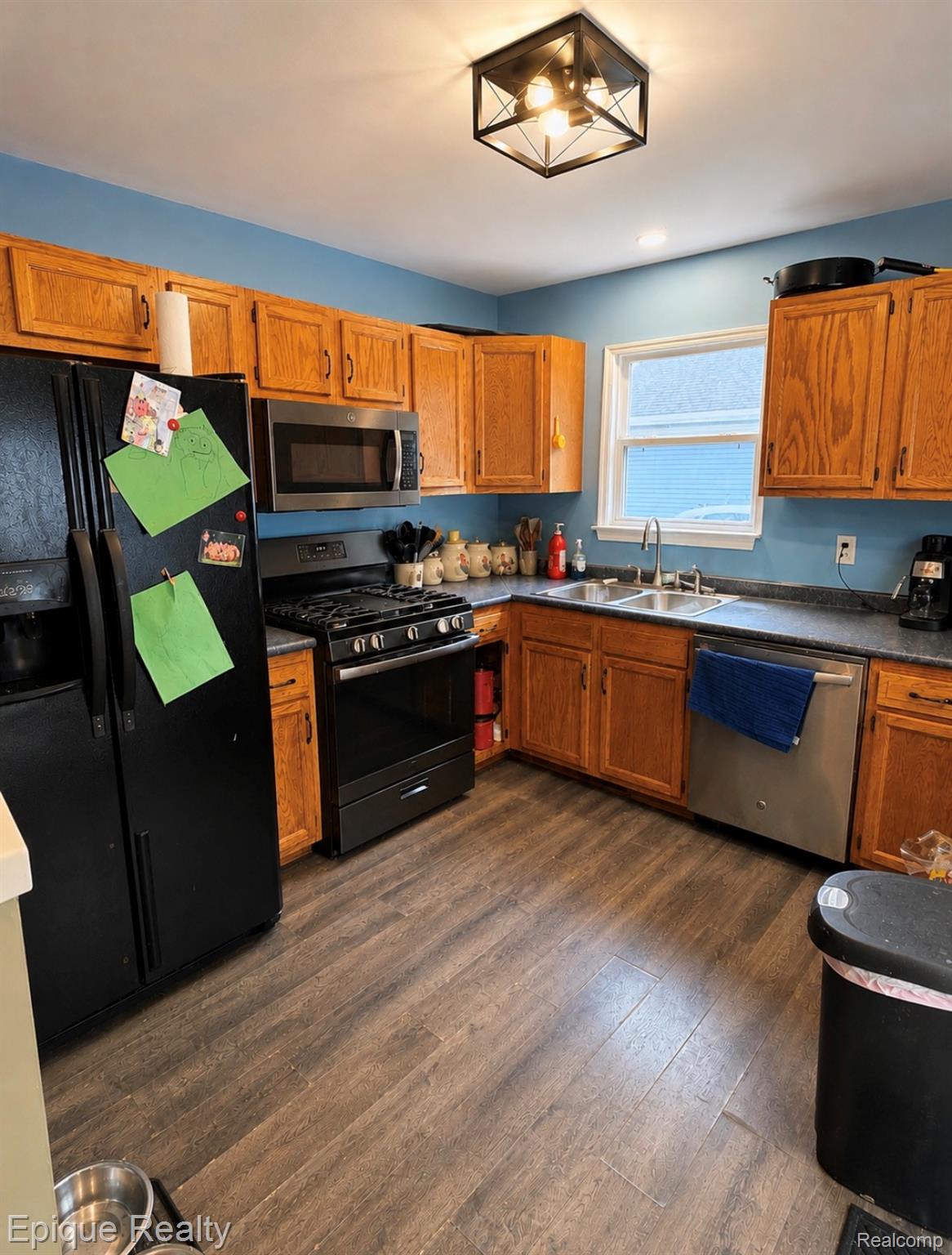 11619 Read Avenue Mount Morris, MI 48458 - Photo 3 of 10 Kitchen featuring wood-finish flooring, natural wood cabinetry, a stainless steel sink, a stainless steel dishwasher, and a window with a white frame