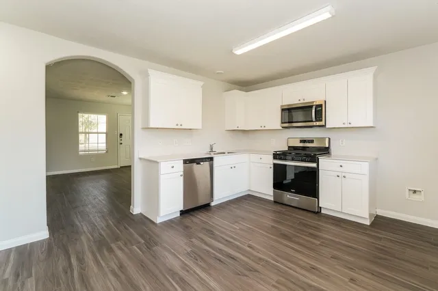 a kitchen with granite countertop a stove top oven a sink dishwasher and a refrigerator with wooden floor