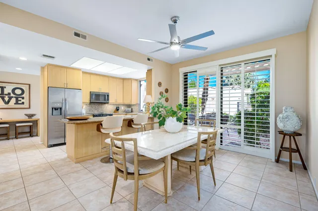 a kitchen with stainless steel appliances granite countertop a stove a refrigerator a sink a dining table and chairs