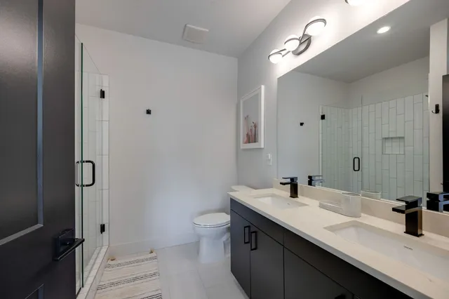 a bathroom with a double vanity sink toilet and mirror