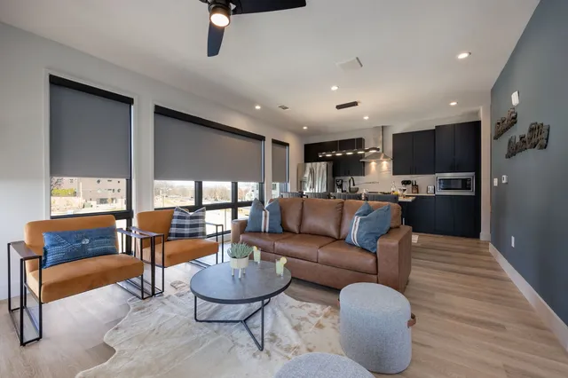 a living room with furniture kitchen view and a large window