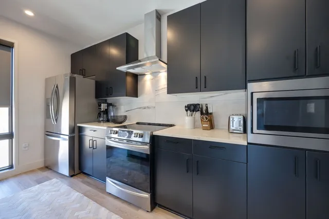 a kitchen with stainless steel appliances granite countertop a refrigerator a stove and a sink with wooden floor