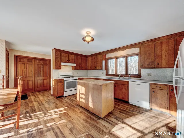 a kitchen with stainless steel appliances granite countertop a stove a sink dishwasher and cabinets with wooden floor