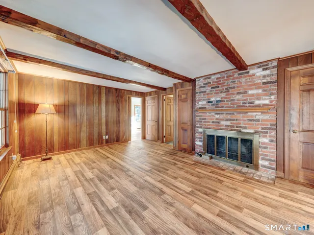 a view of an empty room with wooden floor and a fireplace