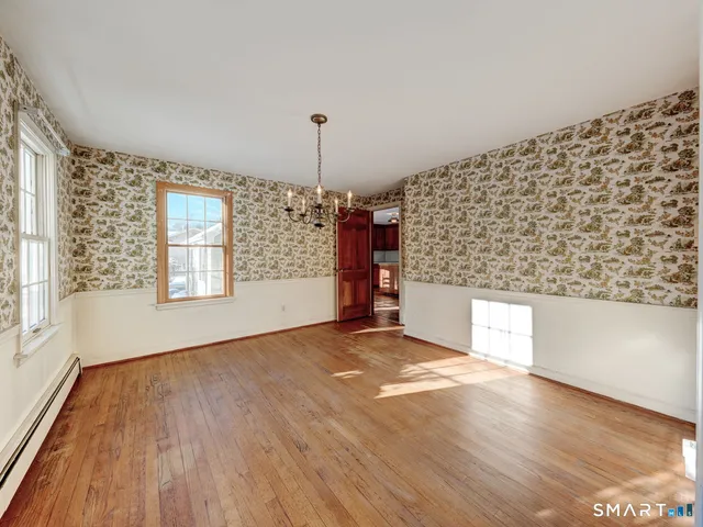 a view of an empty room with window and wooden floor