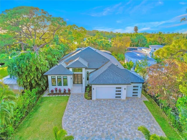 a view of a house with a big yard plants and large tree