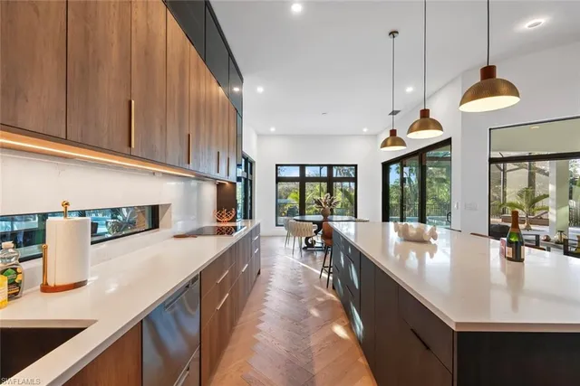 a large kitchen with kitchen island a large window a sink a counter and chairs