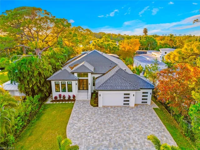 a view of a house with a big yard plants and large tree