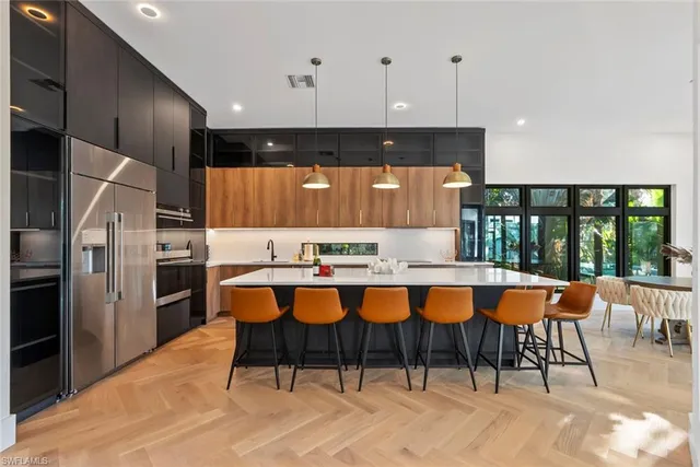 a large kitchen with stainless steel appliances kitchen island granite countertop a table chairs in it and wooden floors