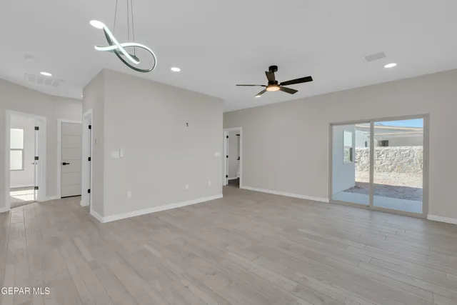 a view of an empty room with a ceiling fan and window