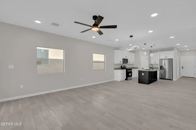 a view of a big room with a ceiling fan and windows