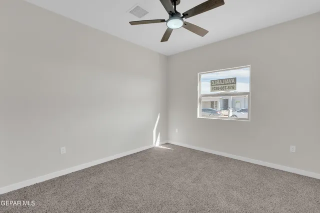 an empty room with a window and a fan