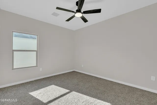 an empty room with a window and a ceiling fan