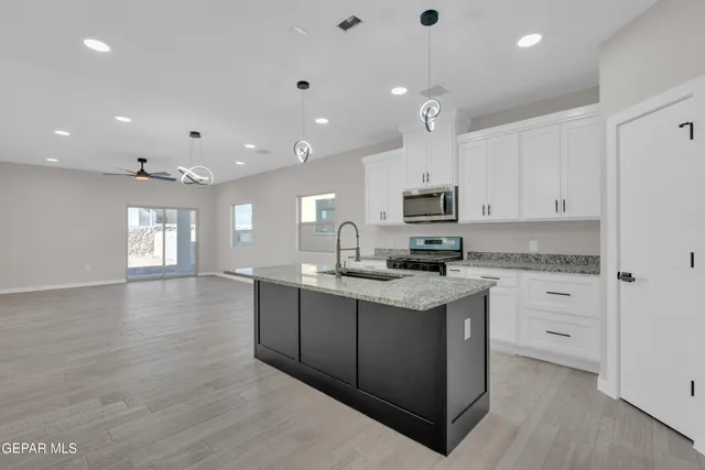 a kitchen with granite countertop a sink dishwasher a stove and a refrigerator with wooden floor