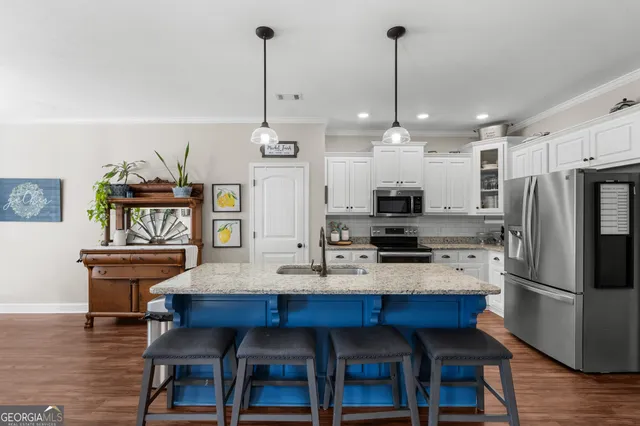 a kitchen with stainless steel appliances kitchen island granite countertop a dining table chairs and refrigerator