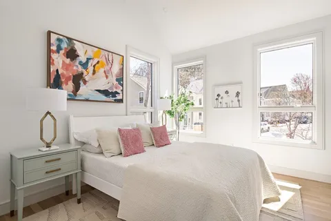 a bedroom with a bed painting on the wall and a window