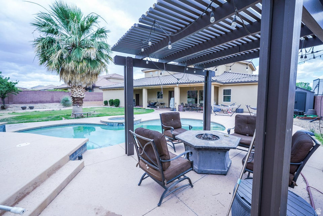 3683 South 2640 West St. George, UT 84790 - Photo 39 of 41 Outdoor living area featuring a custom pergola, integrated fire pit, and a kidney-shaped swimming pool with an attached spa