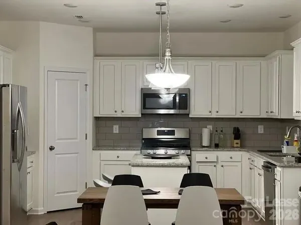 a kitchen with stainless steel appliances granite countertop a refrigerator a stove a sink dishwasher and white cabinets with wooden floor