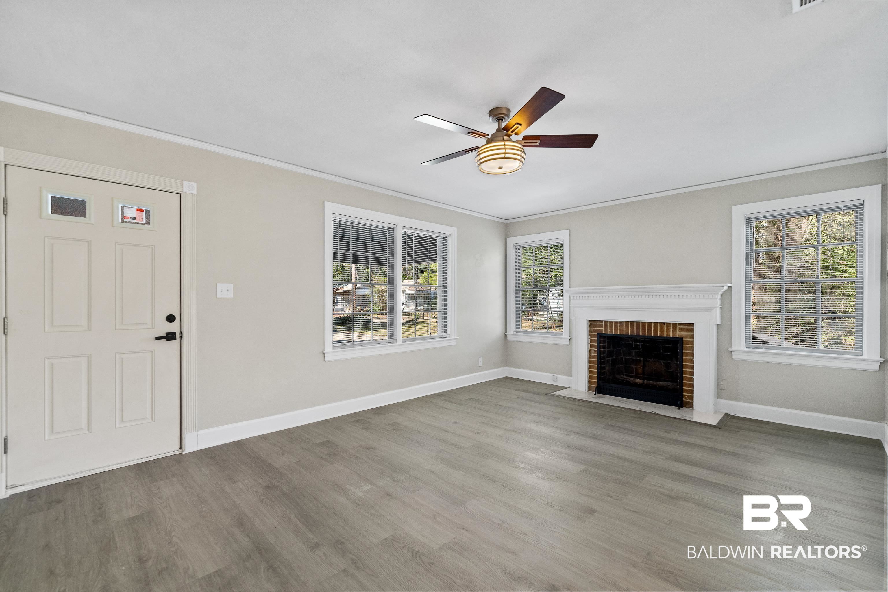 611 Morgan Avenue Mobile, AL 36606 - Photo 7 of 24 Unfurnished living room featuring a wealth of natural light, a brick fireplace, wood-type flooring, and ceiling fan