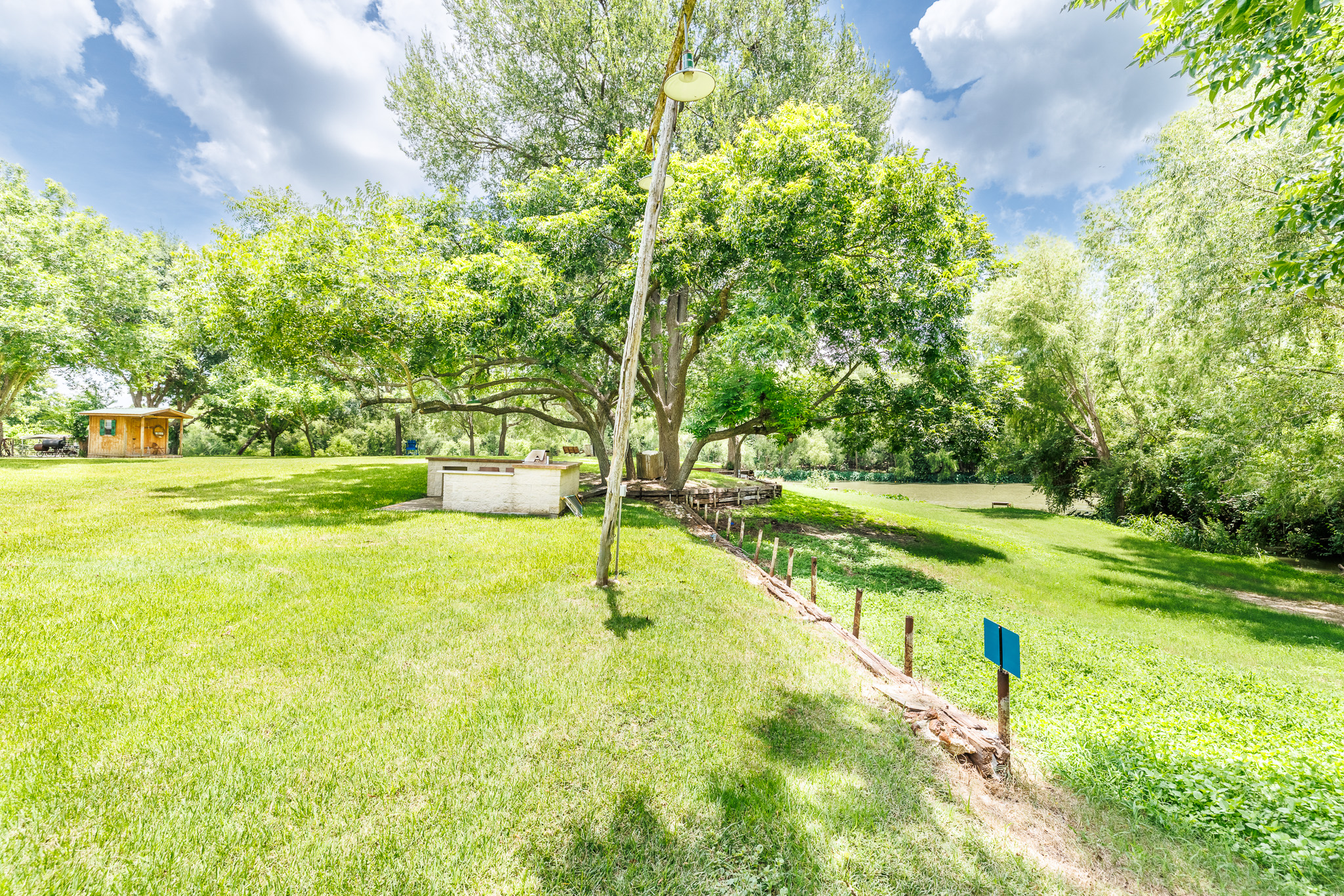 Tbd Goodwin Road Gonzales, TX 78629 - Photo 6 of 33 A verdant, tree-lined landscape descends toward a serene body of water, offering peaceful outdoor living.