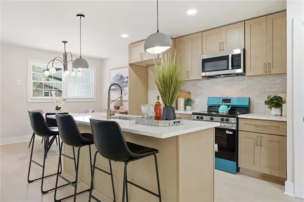 a kitchen with stainless steel appliances granite countertop a stove top oven a sink dishwasher a dining table and chairs with wooden floor