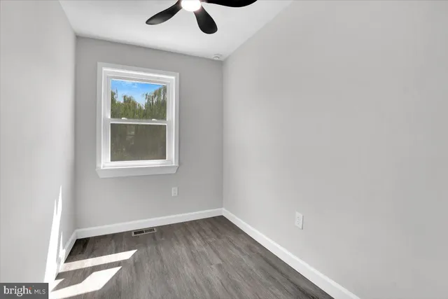a view of empty room with wooden floor and fan