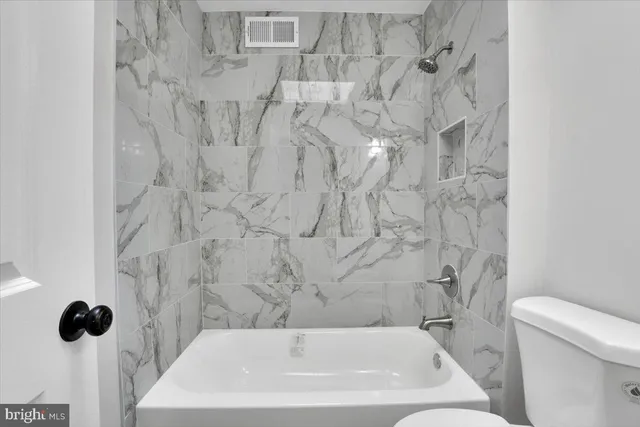 a white toilet sitting next to a bath tub