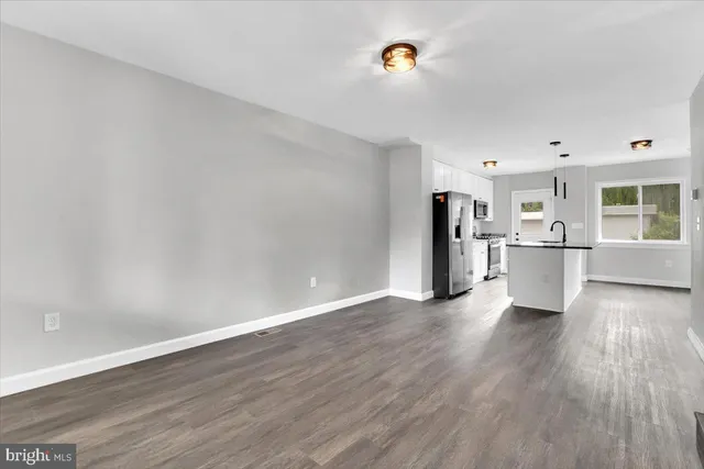 a view of a kitchen with a fridge and wooden floor