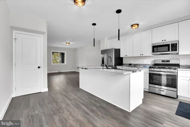 a kitchen with kitchen island a stove a sink and a microwave