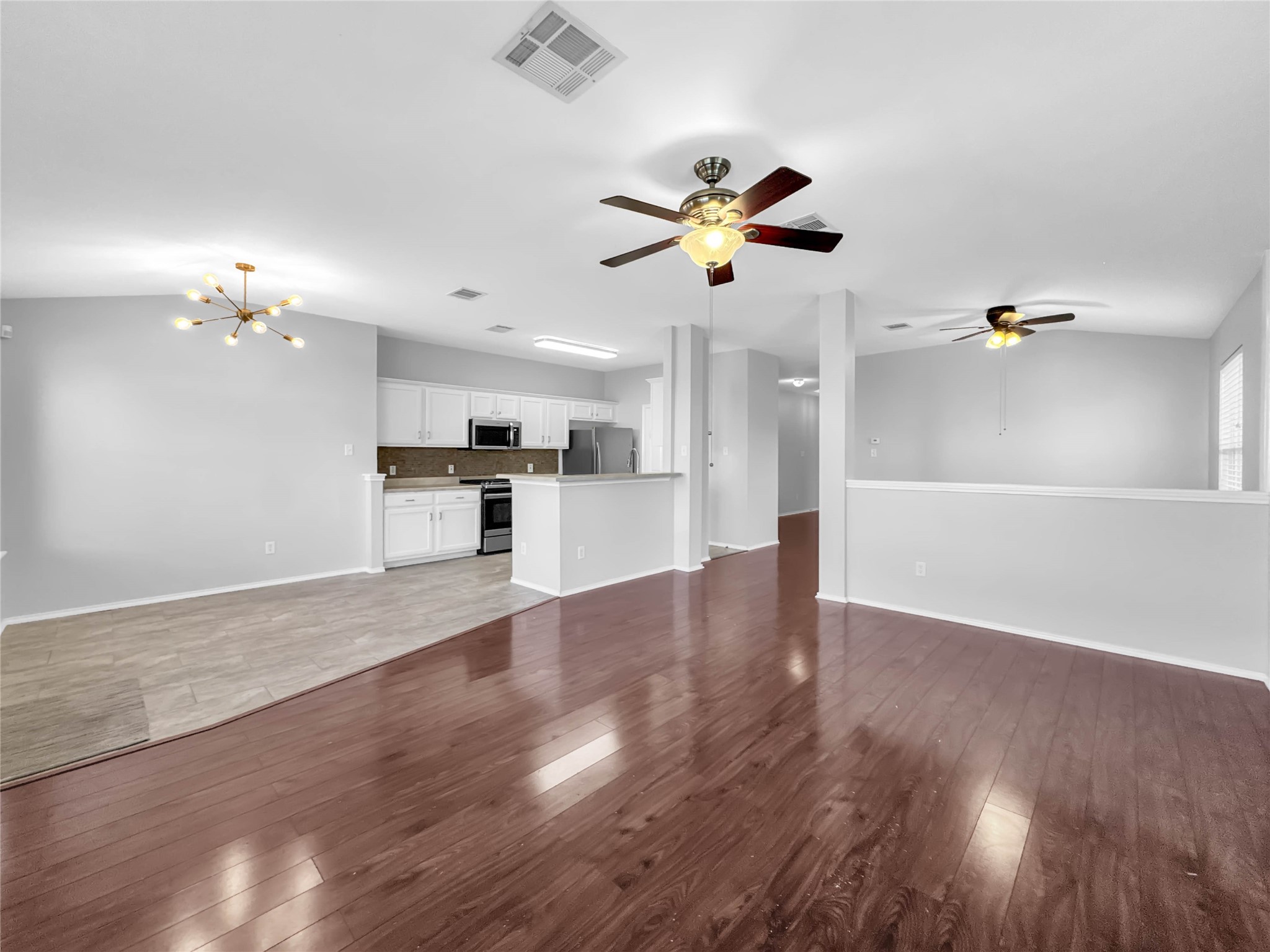 1032 Tudor House Road Pflugerville, TX 78660 - Photo 14 of 32 a view of an empty room and kitchen with wooden floor