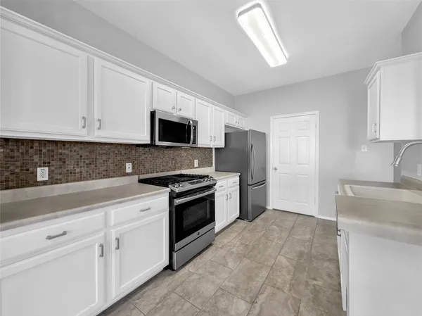 a kitchen with granite countertop a sink a stove top oven and white stainless steel appliances