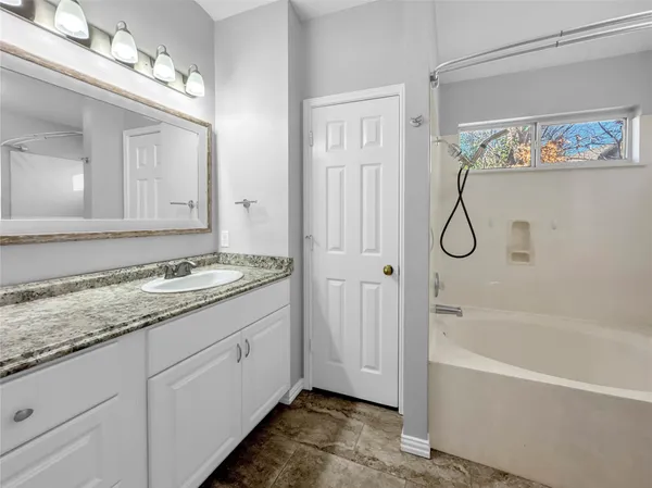 a bathroom with a granite countertop sink mirror and a bathtub