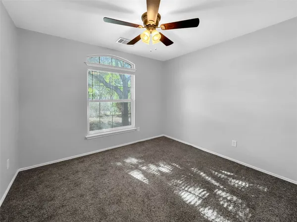 a view of an empty room with window and chandelier fan