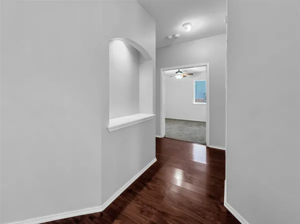 a view of a hallway with wooden floor and a bathroom