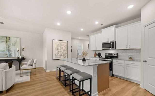 1260 Riverstone Road Jonesboro, GA 30236 - Photo 4 of 45 a kitchen with stainless steel appliances kitchen island granite countertop a stove a sink a dining table and chairs